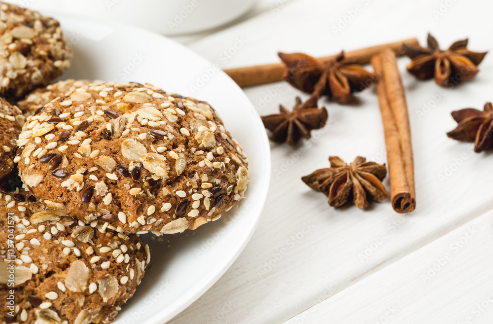 Oatmeal cookies with sesame, nuts, cinnamon and star anise on a white wooden table, close-up shot Oatmeal cookies with sesame, nuts, cinnamon and star anise on a white wooden table, close-up shot
