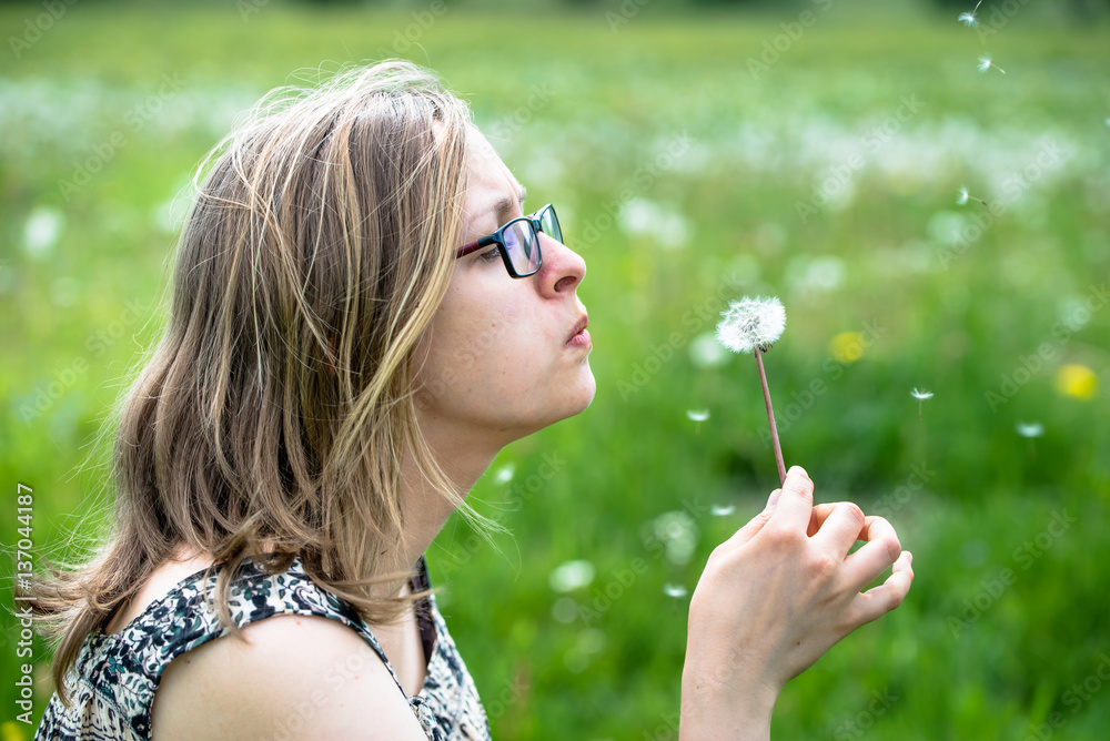 Beautiful woman blowing dandelion on meadow in spring Beautiful woman blowing dandelion on meadow in spring