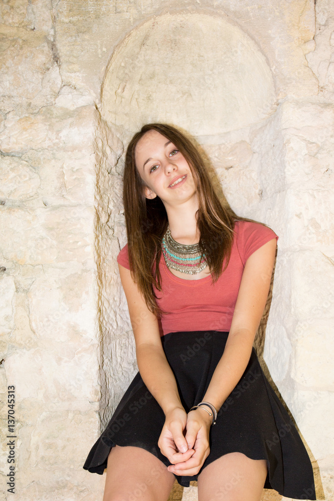 teenage girl in a skirt and sitting against a wall in city teenage girl in a skirt and sitting against a wall in city