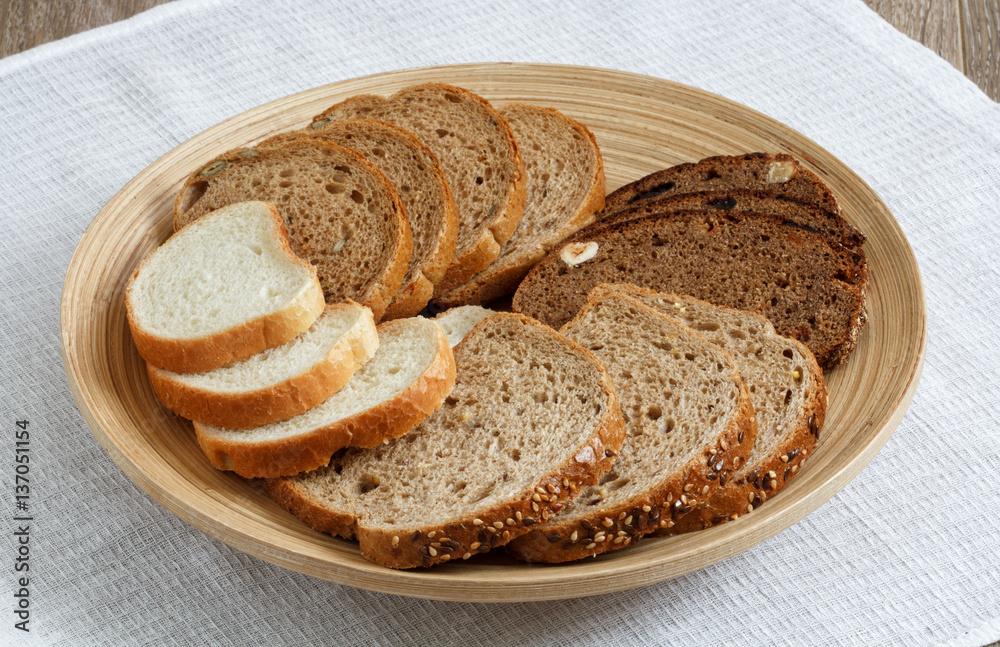 Different types of bread on a plate on a table surface, top view