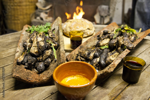 Calçots in a tires with bread, romesco sauce and wine front of a fire. photo