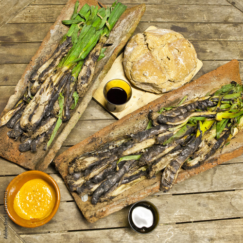 Calçots in a tires with bread, romesco sauce and wine photo