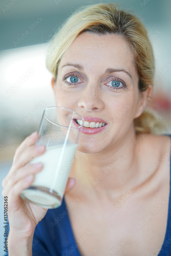 Portrait of blond mature woman drinking milk from glass