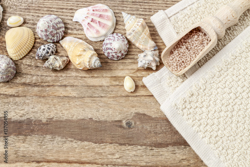 Tiny shells and scoop of sea salt on wooden background.