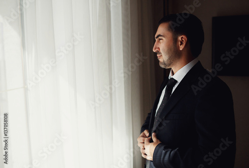 The groom standing near window