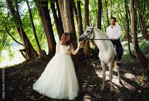 The groom riding a horse on the forest © myronovychoksana