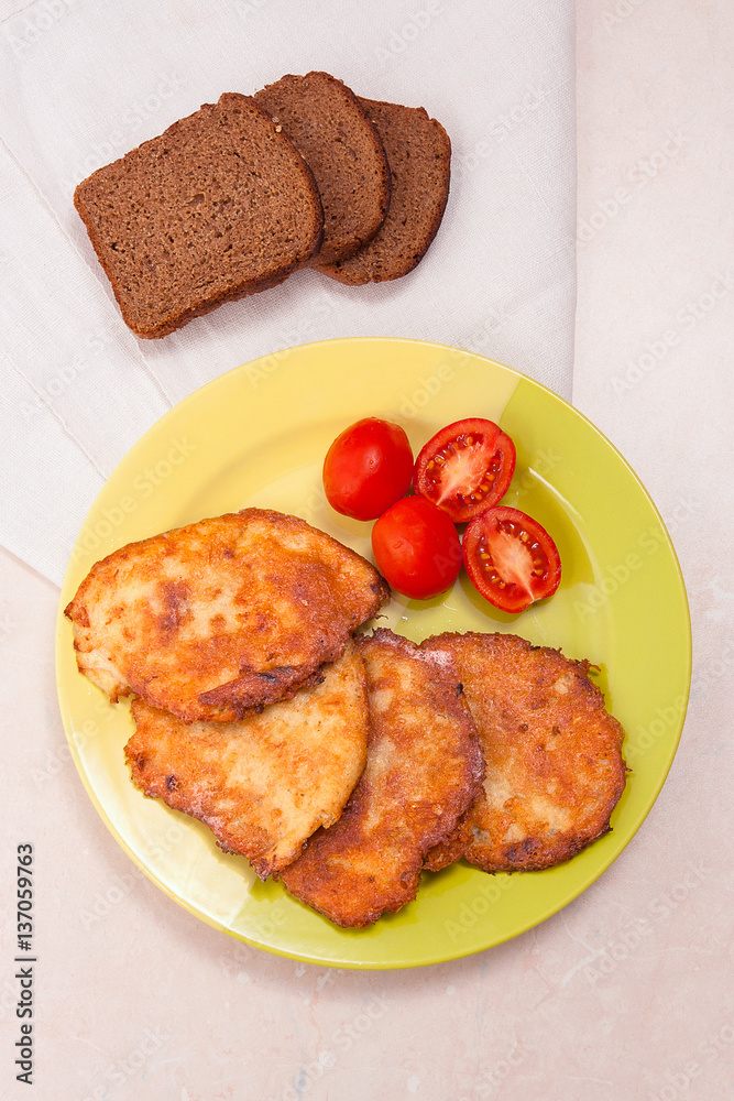 Potato pancakes with meat and tomatoes on green plate with rye b Potato pancakes with meat and tomatoes on green plate with rye b