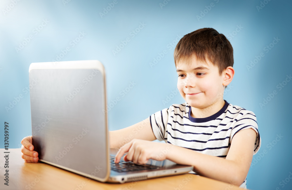 seven years old child sitting with a laptop at table and typing seven years old child sitting with a laptop at table and typing