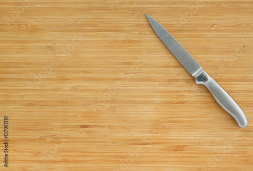 Steel kitchen knives on a wood board, top view