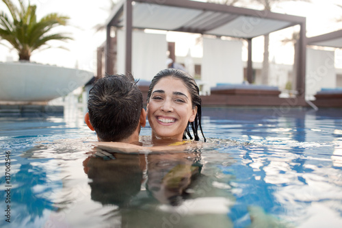 Expat couple embracing in swimming pool.