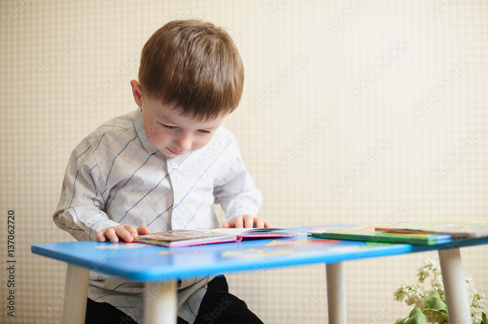 little boy sitting at the desk and reading a book little boy sitting at the desk and reading a book