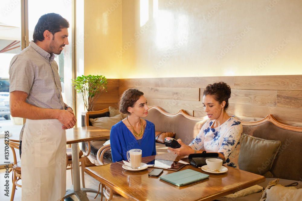 Expat woman paying using credit card reader at restaurant. Expat woman paying using credit card reader at restaurant.