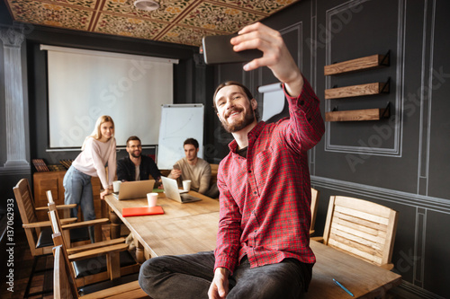 Happy man sitting in office and make a selfie