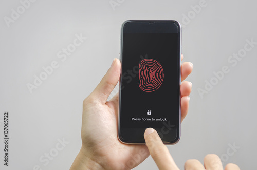 Female scanning fingerprint on smartphone, on gray background. Unlock mobile phone.