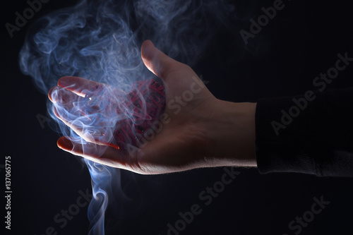 male hand with decorative valentines day red heart in smoke