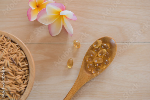 rice bran oil capsules and paddy Natural Supplement on wooden background.
