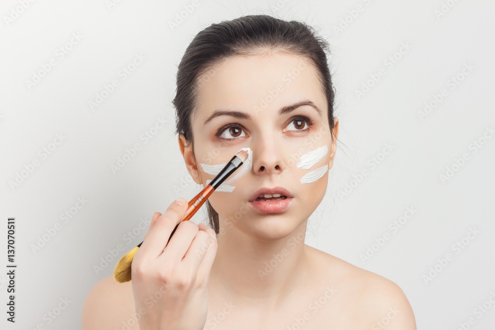woman with brush in hand and white lines on face