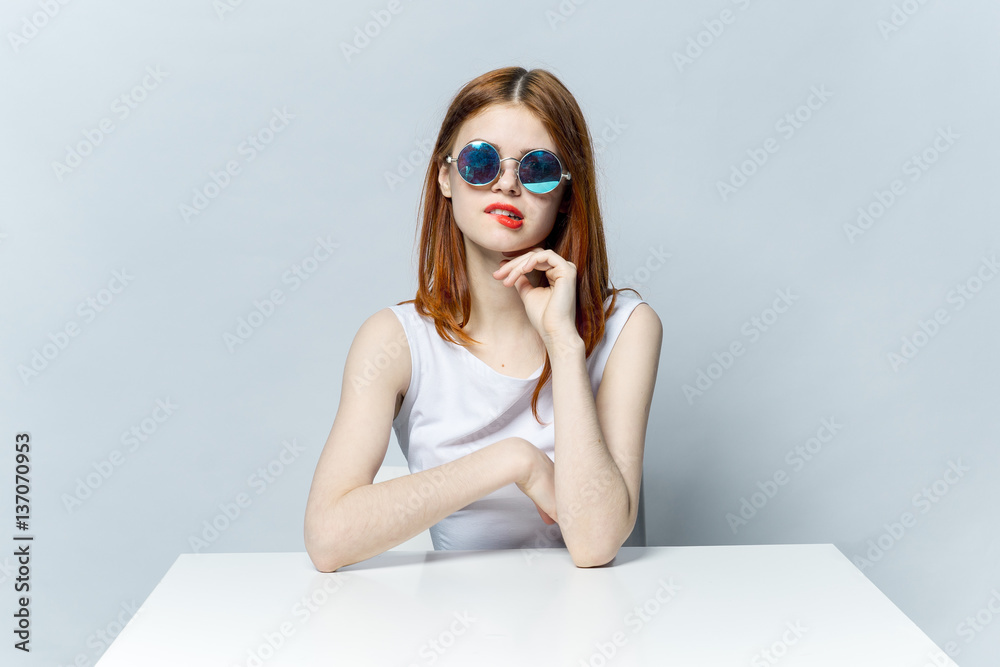 woman sitting at a table in round glasses twisting her lips woman sitting at a table in round glasses twisting her lips