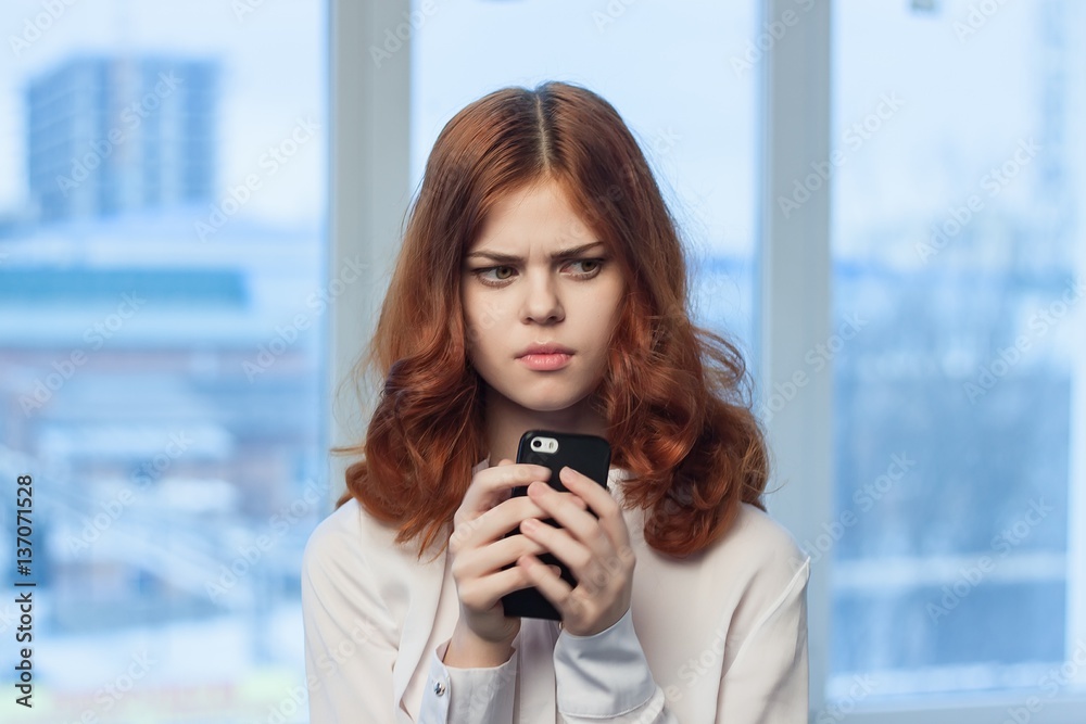 woman looks at camera and phone in hand