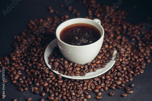 a cup of coffee with scattered coffee beans