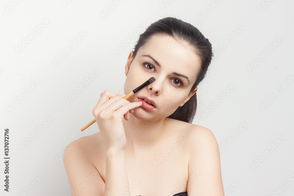 woman holds brush for make-up on face woman holds brush for make-up on face