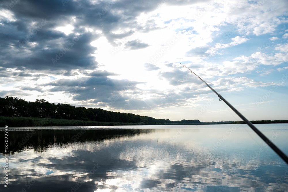 Fisherman sport hobby fishing rod or spinning reel on the river. Fishing on sunrise. beautiful sunrise on the river is reflected in water. Fisherman sport hobby fishing rod or spinning reel on the river. Fishing on sunrise. beautiful sunrise on the river is reflected in water.