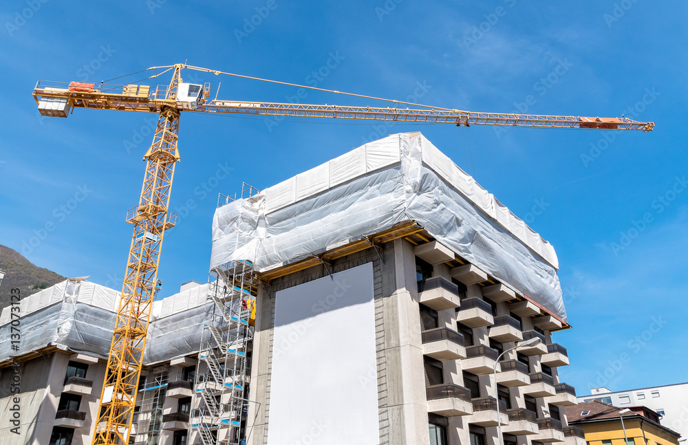 Fototapeta premium Crane and building construction site against blue sky