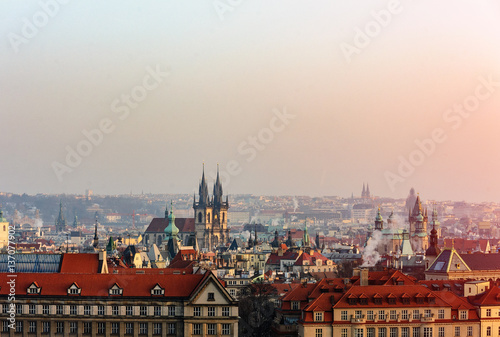 A view on the Prague roofs and street in the sunset through the fog