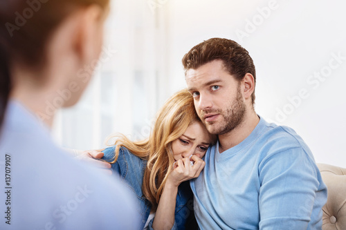 Depressed handsome man hugging his wife