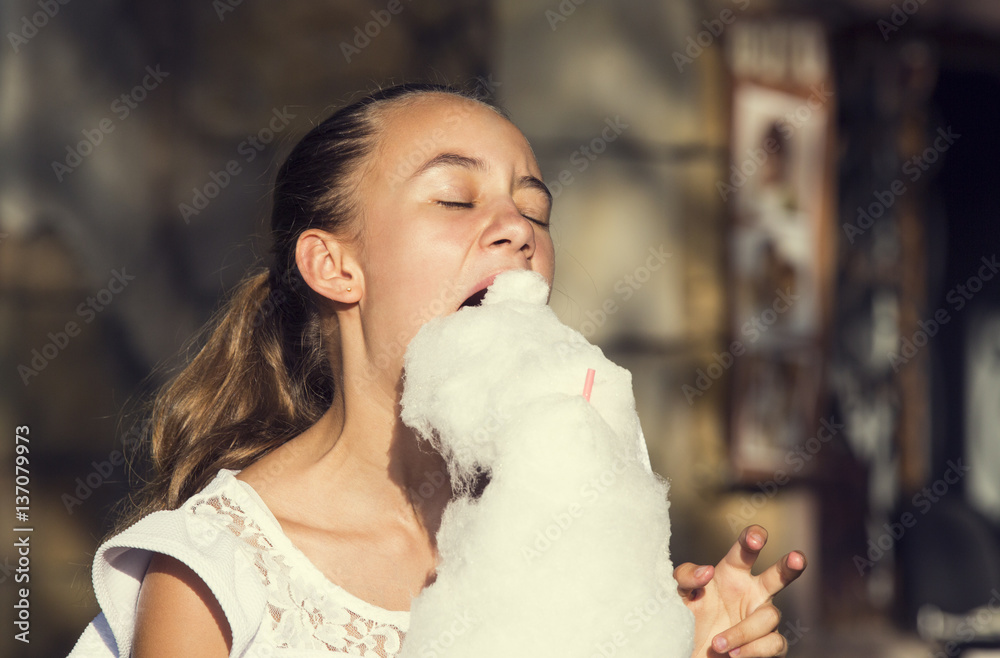 Girl eating cotton candy in a summer park Girl eating cotton candy in a summer park