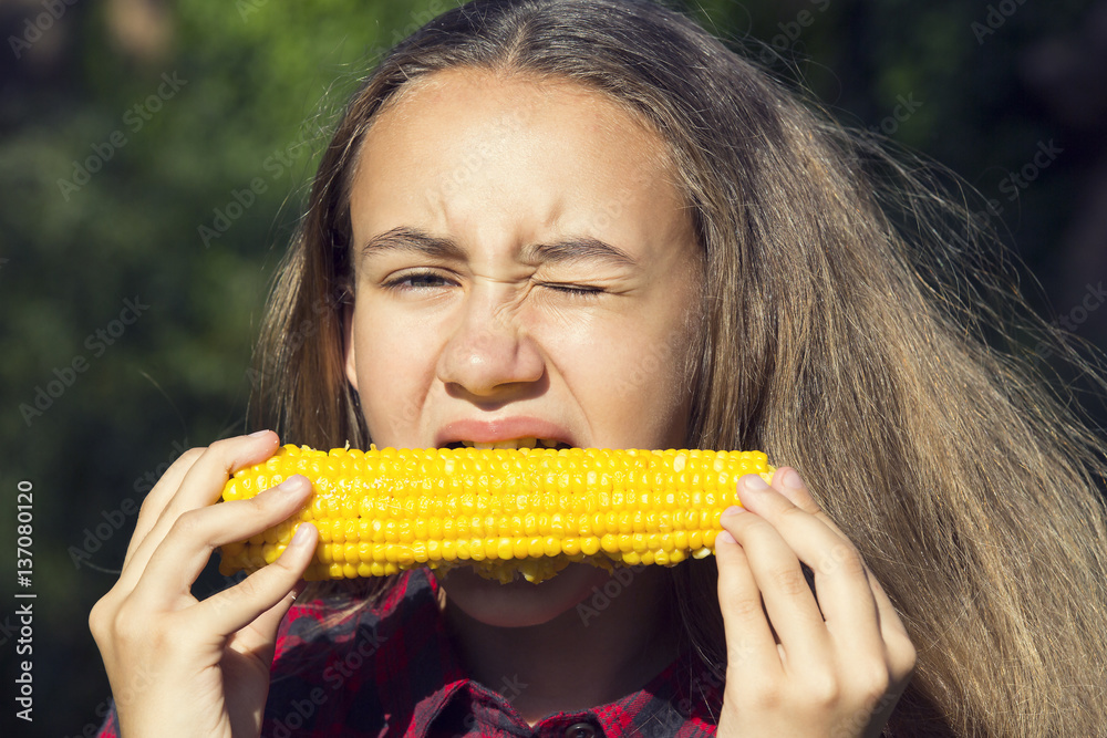 Girl eating sweet corn on the nature of the day Girl eating sweet corn on the nature of the day