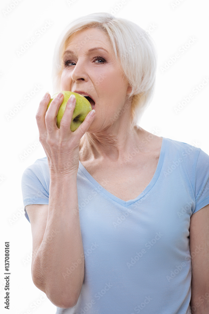 Portrait of elderly woman while biting green apple Portrait of elderly woman while biting green apple