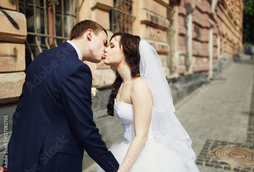 Newlyweds kissing walking city streets
