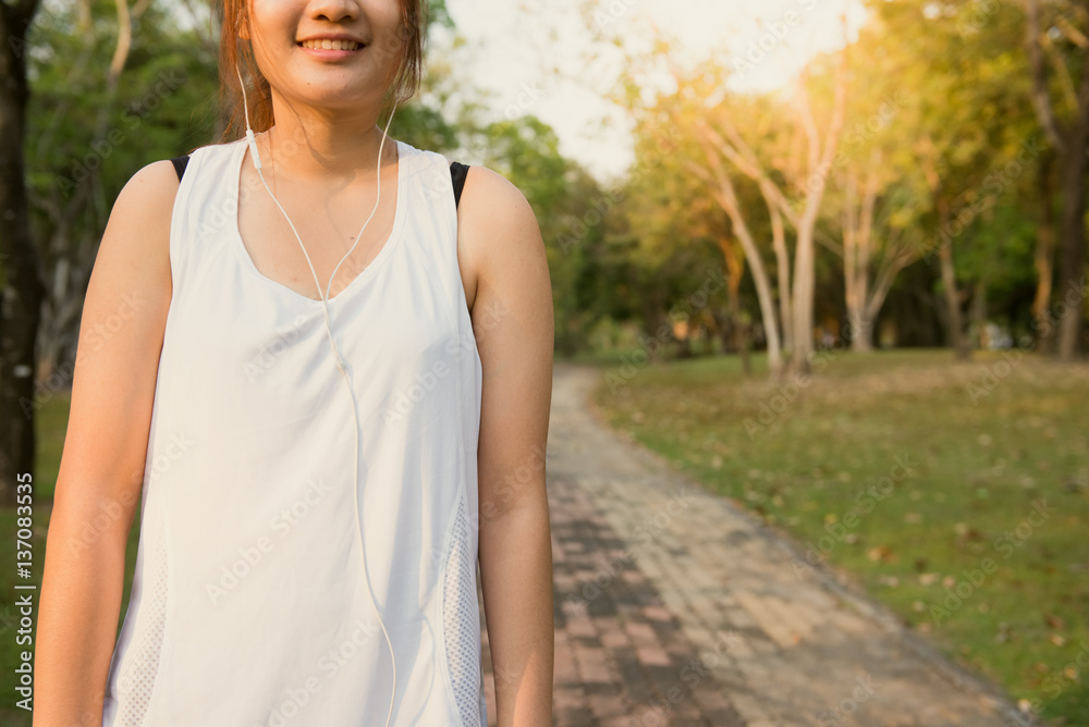 Happy sporty woman wearing smartphone armband and earphones before running in autumn. Female athlete listening music during fitness training outdoor. Vintage effect style pictures.