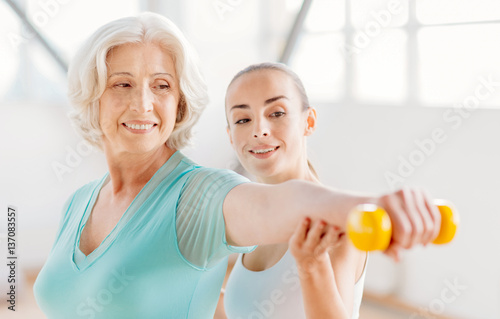Fototapeta Naklejka Na Ścianę i Meble -  Delighted pleasant woman exercising with a dumbbell