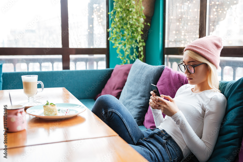 Relaxed woman sitting and using cell phone in cafe Relaxed woman sitting and using cell phone in cafe