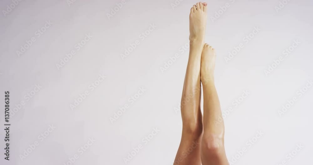 The young woman with perfect body applying a shaving cream on her legs isolated on a white background. Concept of depilation, smooth skin, skincare, cosmetics, wellness center, healthy lifestyle