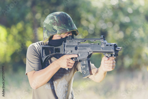 Man in mask aiming with rifle outdoors