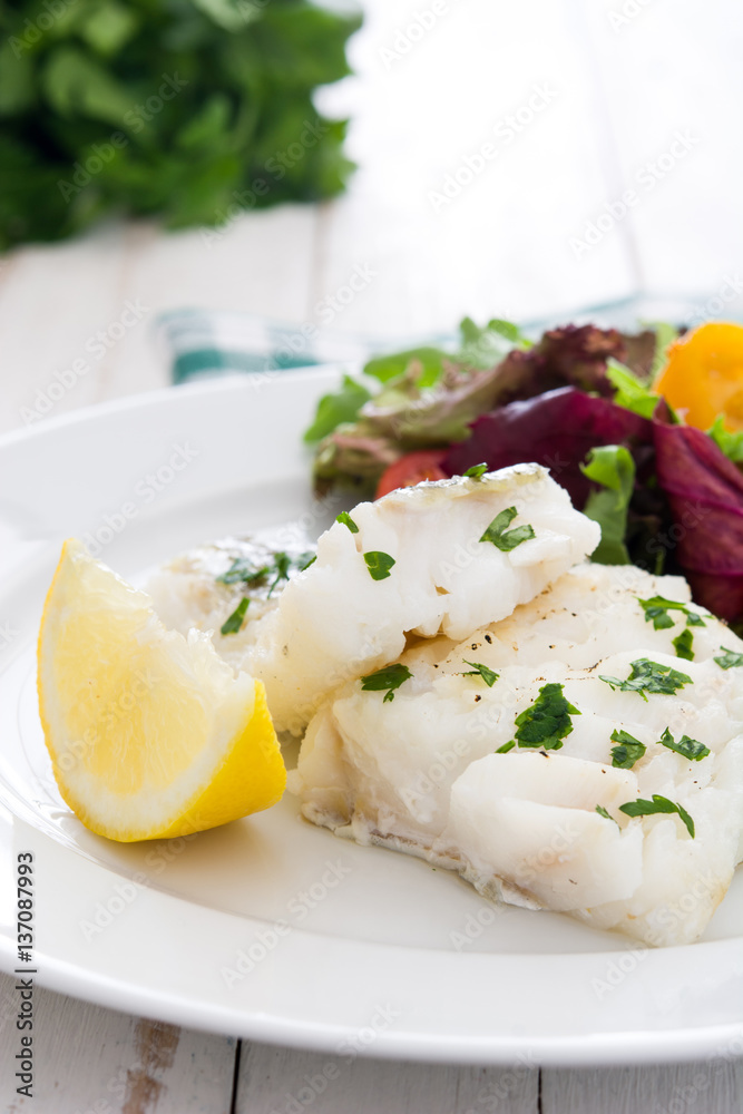 Fried cod fillet and salad in plate on white wooden background
Fried cod fillet and salad in plate on white wooden background