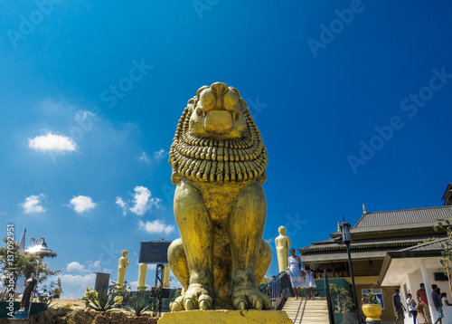 Brave Lion Posture sitting Statue on a mountain view top cliff with sun shine on top blue sky and clouds at Nelligala International Buddhist Center Kandy, Sri Lanka photo
