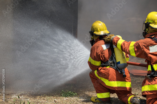 firefighter team water spray by high pressure fire hose