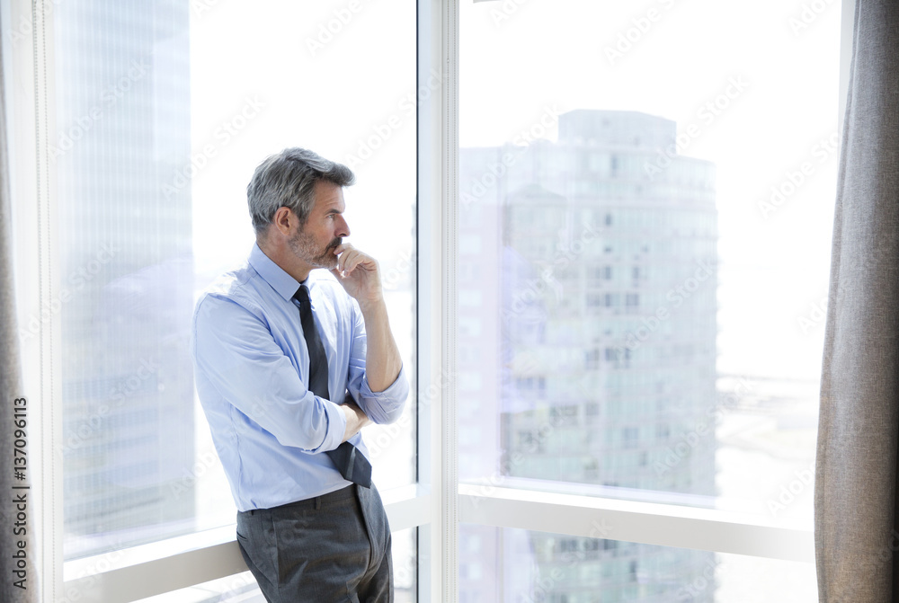 Business man gazing out of high-rise apartment building Business man gazing out of high-rise apartment building