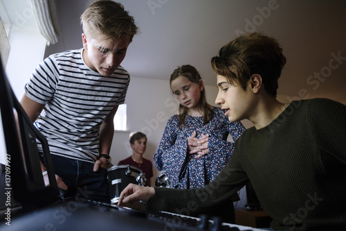 Young friend explaining siblings while playing piano keyboard at home photo