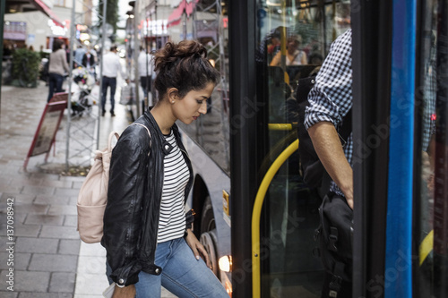 Woman and man boarding bus at city