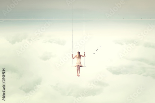 upside down surrealistic minimal woman swings in the air photo