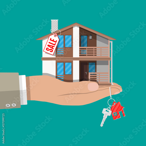 Hand with small house, keys and price tag