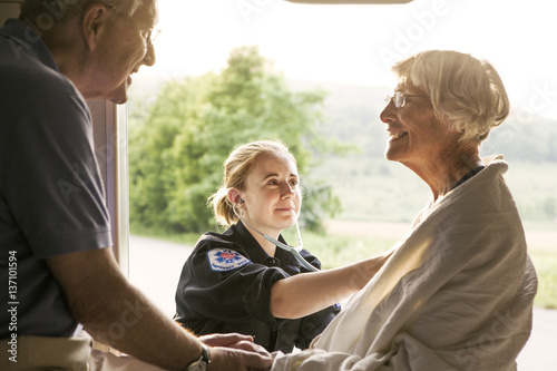 Paramedic taking care of senior patient sitting in ambulance photo