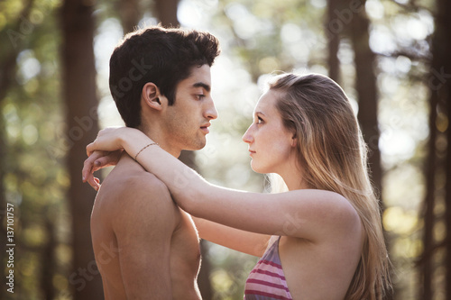 Young man face to face with his girlfriend (16-17) in forest