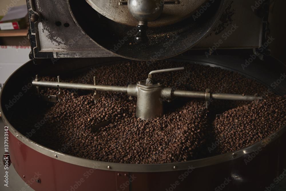 A coffee shop. A metal drum with roasting coffee beans and a central ...