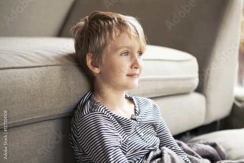 Portrait of boy ( 8-9 ) sitting in front of sofa